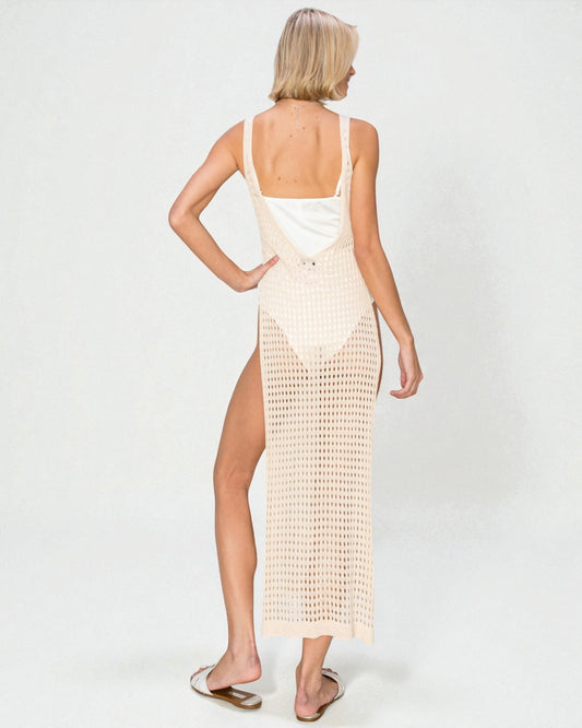 Woman wearing a beige crochet dress with a white top on a white background