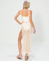Woman wearing a beige crochet dress with a white top on a white background