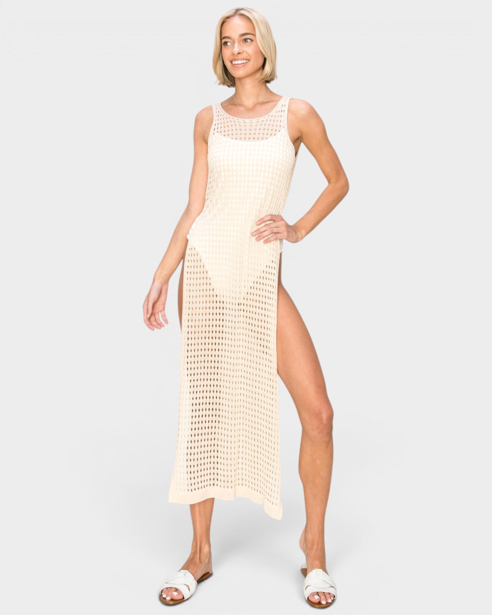 Woman wearing a beige sleeveless dress with a slit on a white background