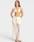 Woman wearing a white bikini and matching pants on a light gray background