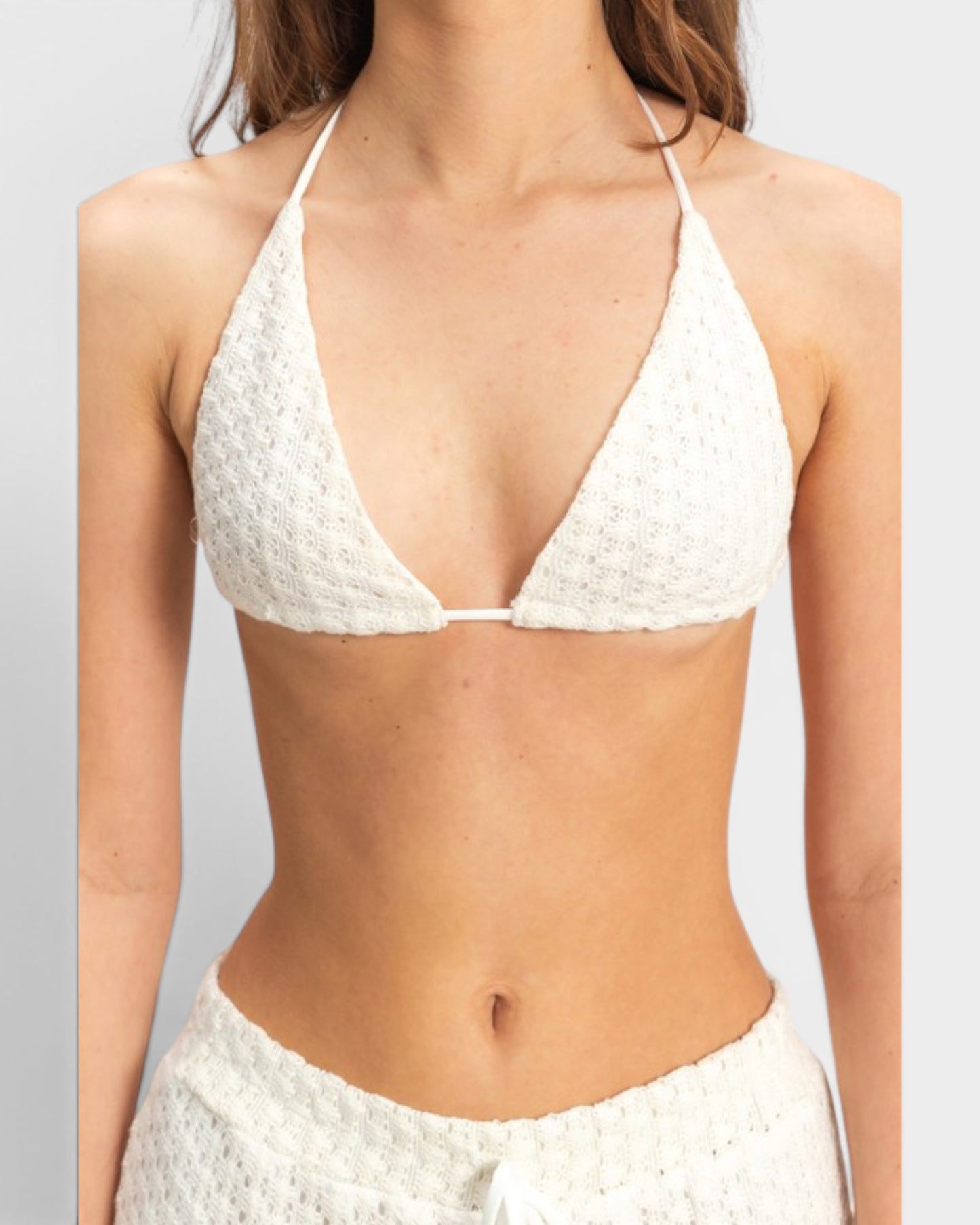 White textured bikini top worn by a person on a plain background