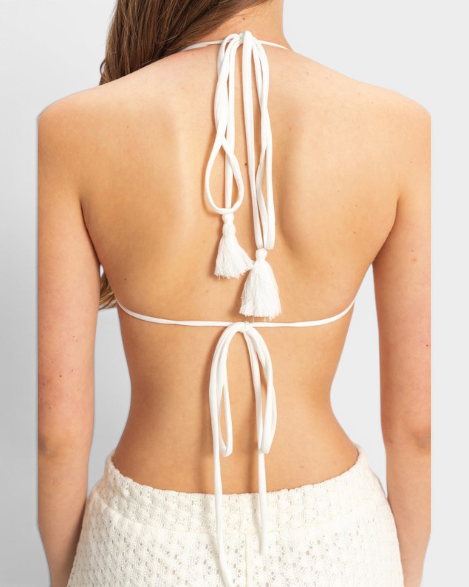 White bikini top with tassels on a plain background