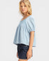 Woman wearing a light blue top and dark denim shorts on a white background