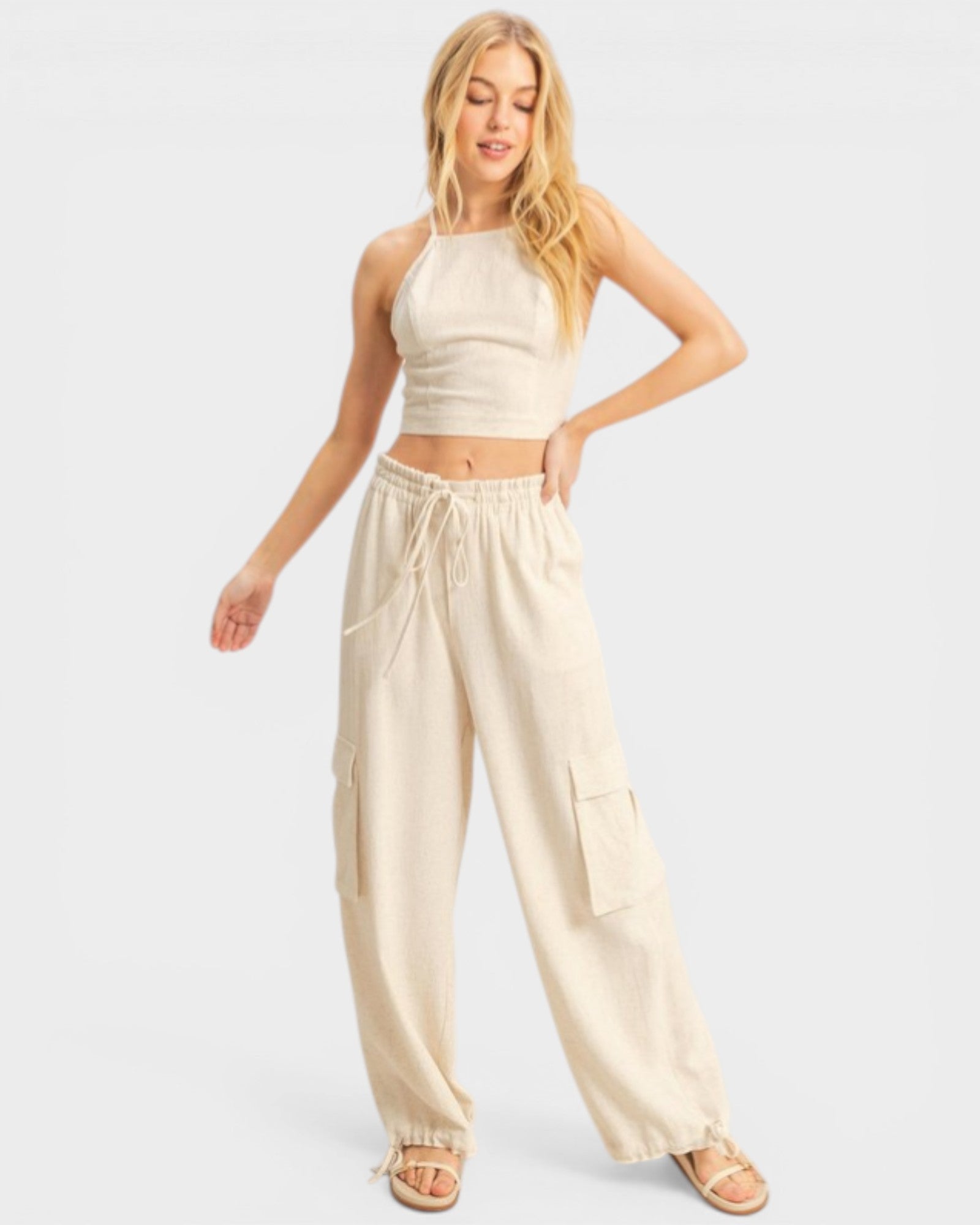 Woman wearing a beige halter top and wide-leg pants on a white background