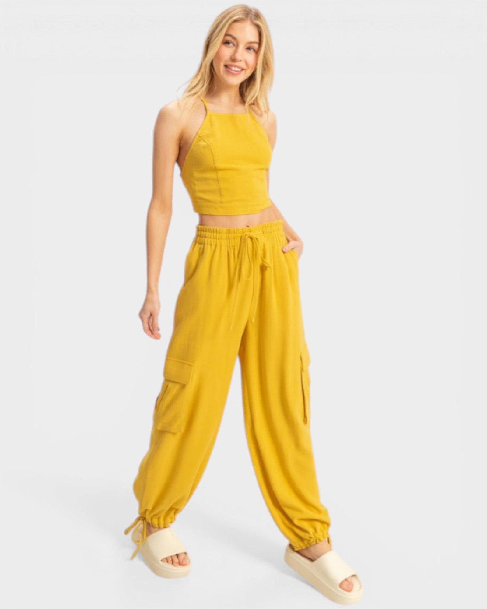 Woman wearing a yellow outfit with a top and wide-leg pants on a white background