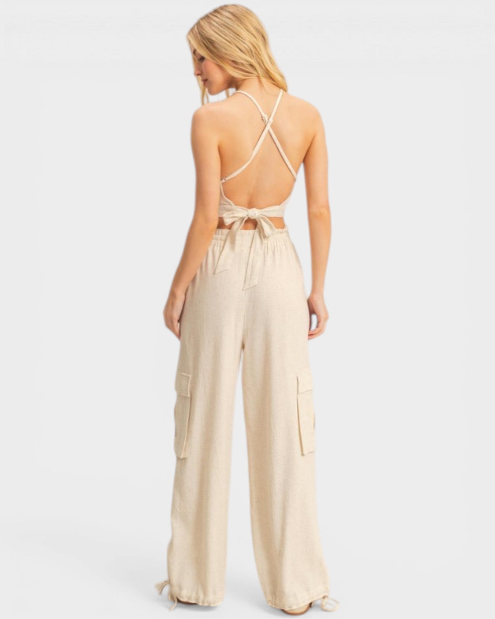 Woman wearing a beige jumpsuit with thin straps on a white background