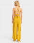 Yellow jumpsuit with open back worn by a person on a light gray background