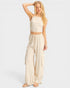 Woman wearing a beige sleeveless top and wide-leg pants on a white background