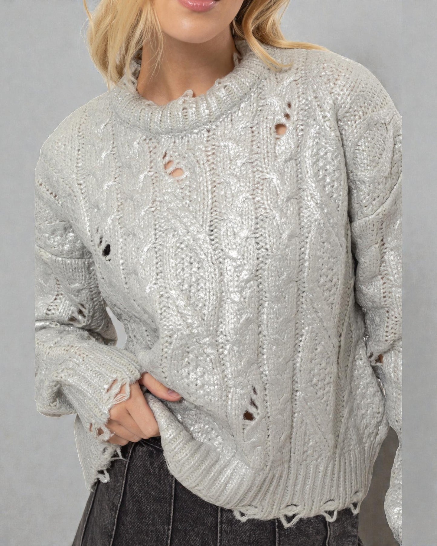 Person wearing a light gray distressed sweater against a plain background