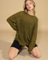 Woman wearing a green knitted sweater and black shorts on a beige background