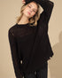 Woman wearing a black knit sweater against a beige background