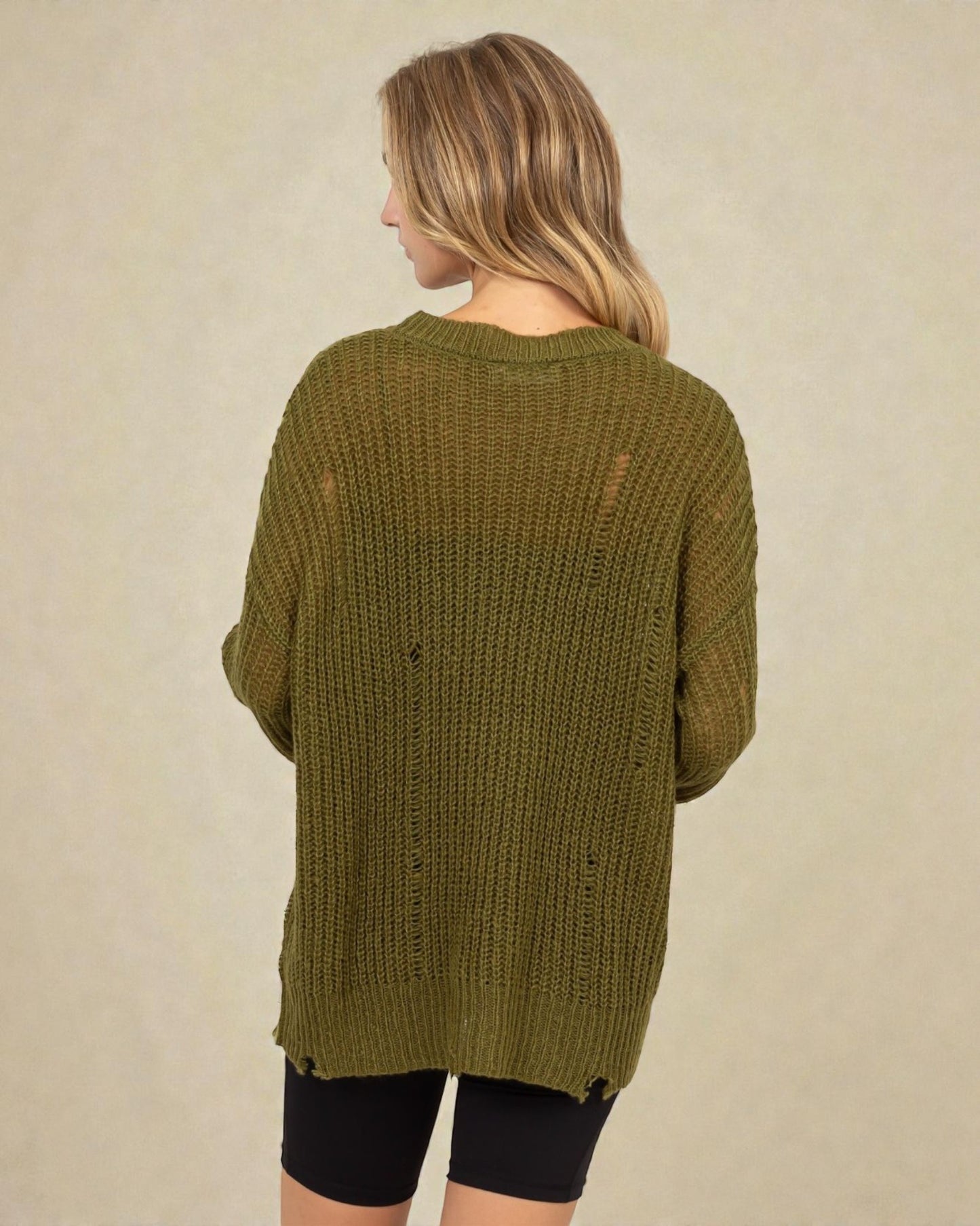 Person wearing a green knitted cardigan on a beige background