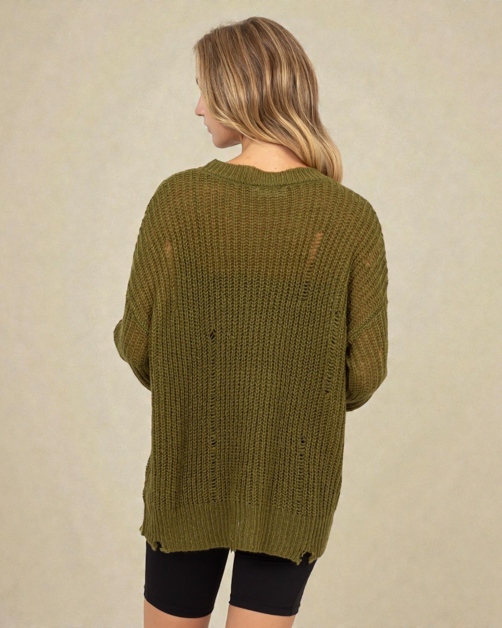 Person wearing a green knitted cardigan on a beige background