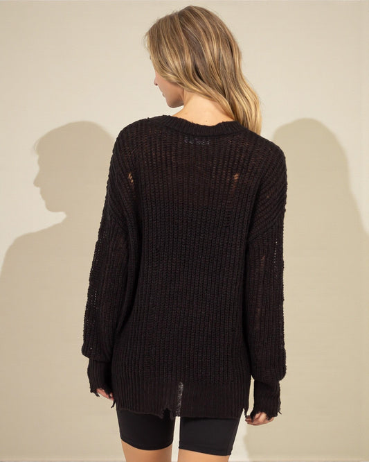 Person wearing a dark brown distressed sweater against a plain background