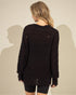 Person wearing a dark brown distressed sweater against a plain background