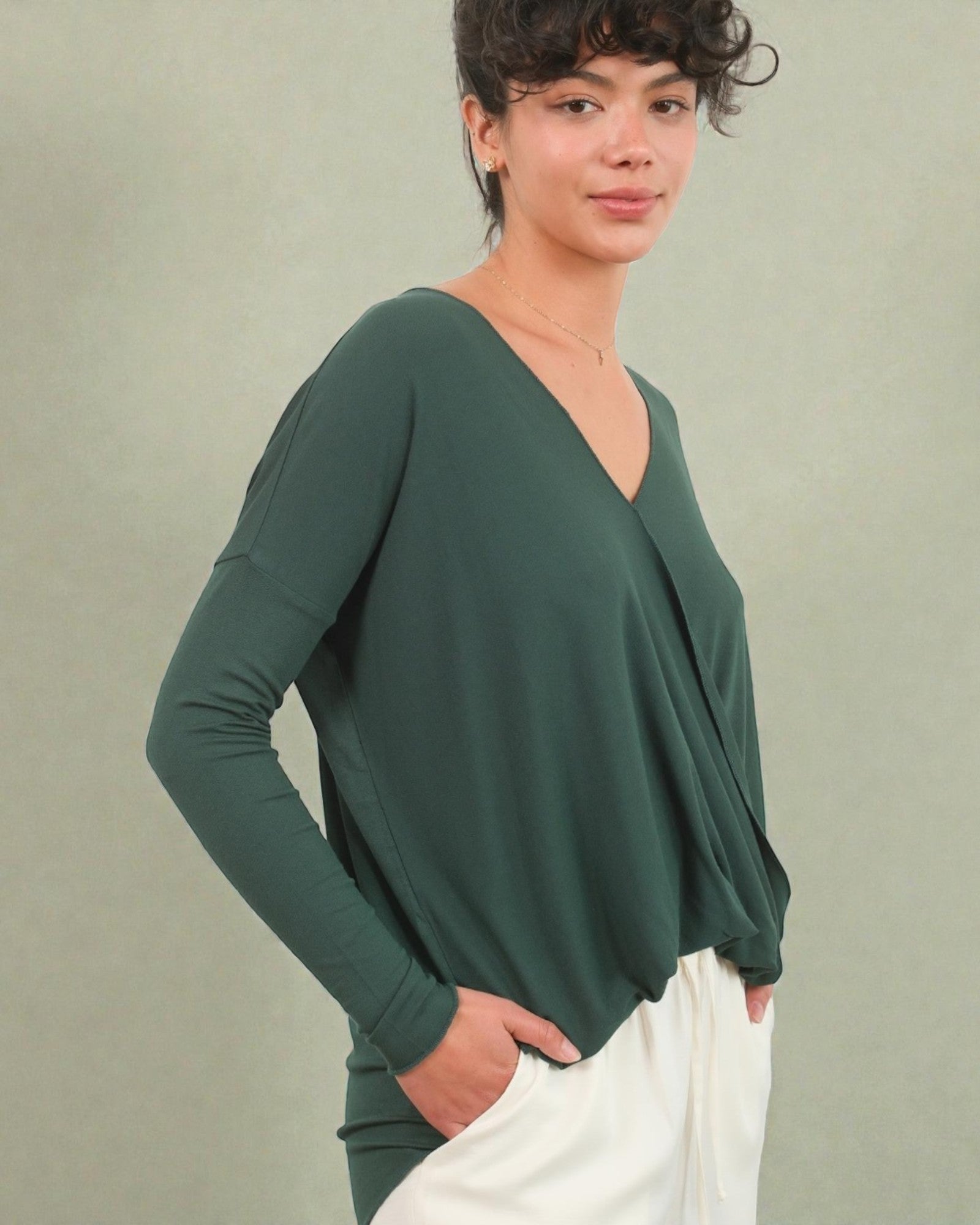 Woman wearing a green long-sleeve top against a plain background
