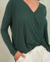 Person wearing a green long-sleeve top with a plain background