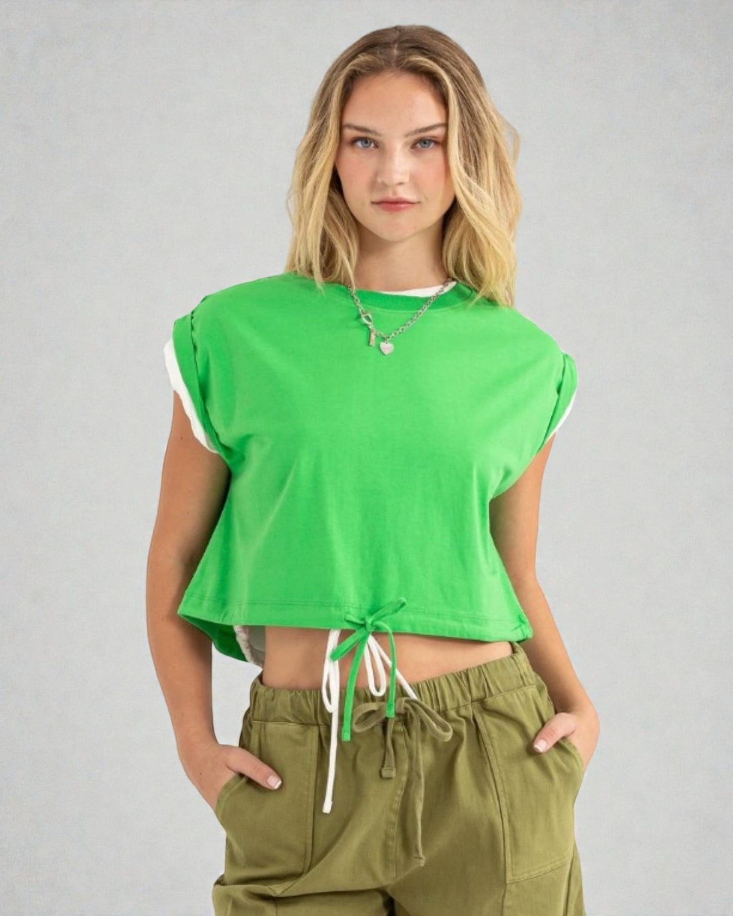 Woman wearing a green crop top and olive green pants on a gray background