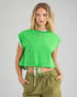Woman wearing a green crop top and olive green pants on a gray background