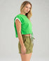 Woman wearing a green crop top and olive green shorts on a gray background