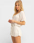 Woman wearing a white romper on a plain background