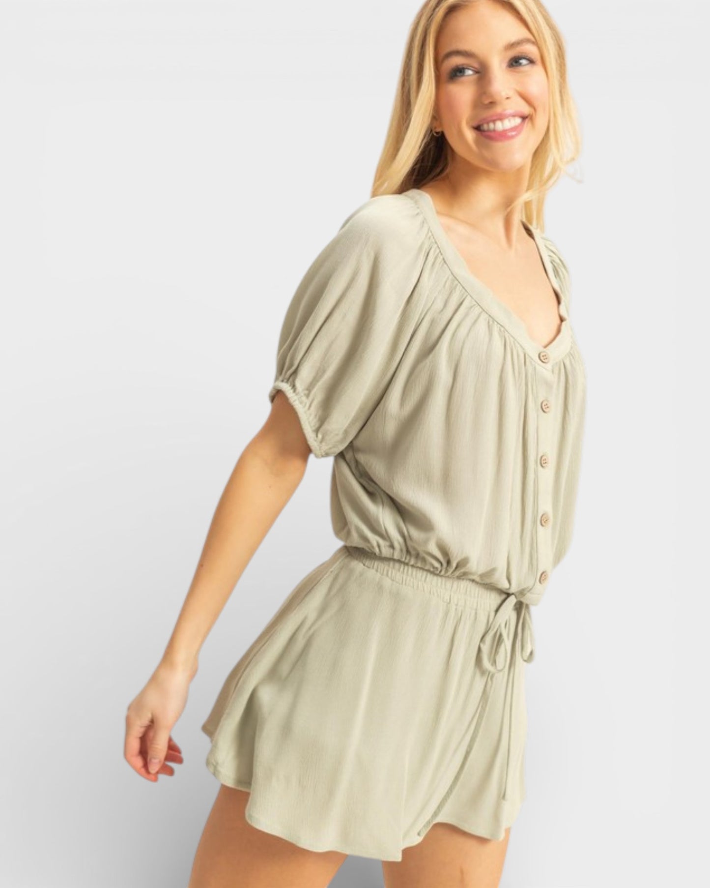 Woman wearing a light green romper against a plain background