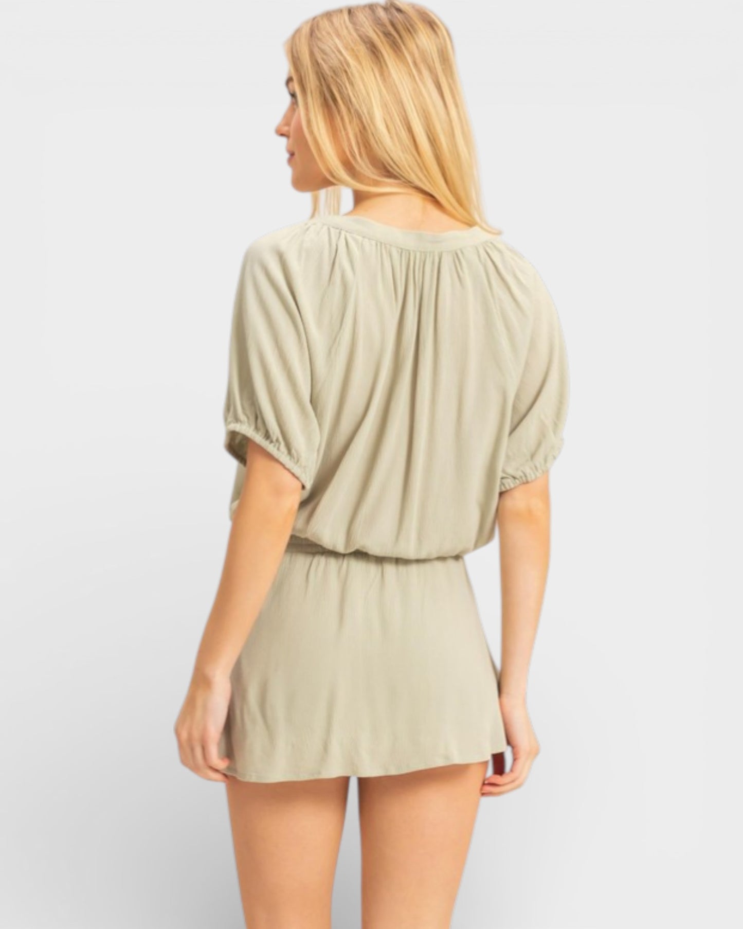 Woman wearing a beige romper on a plain background