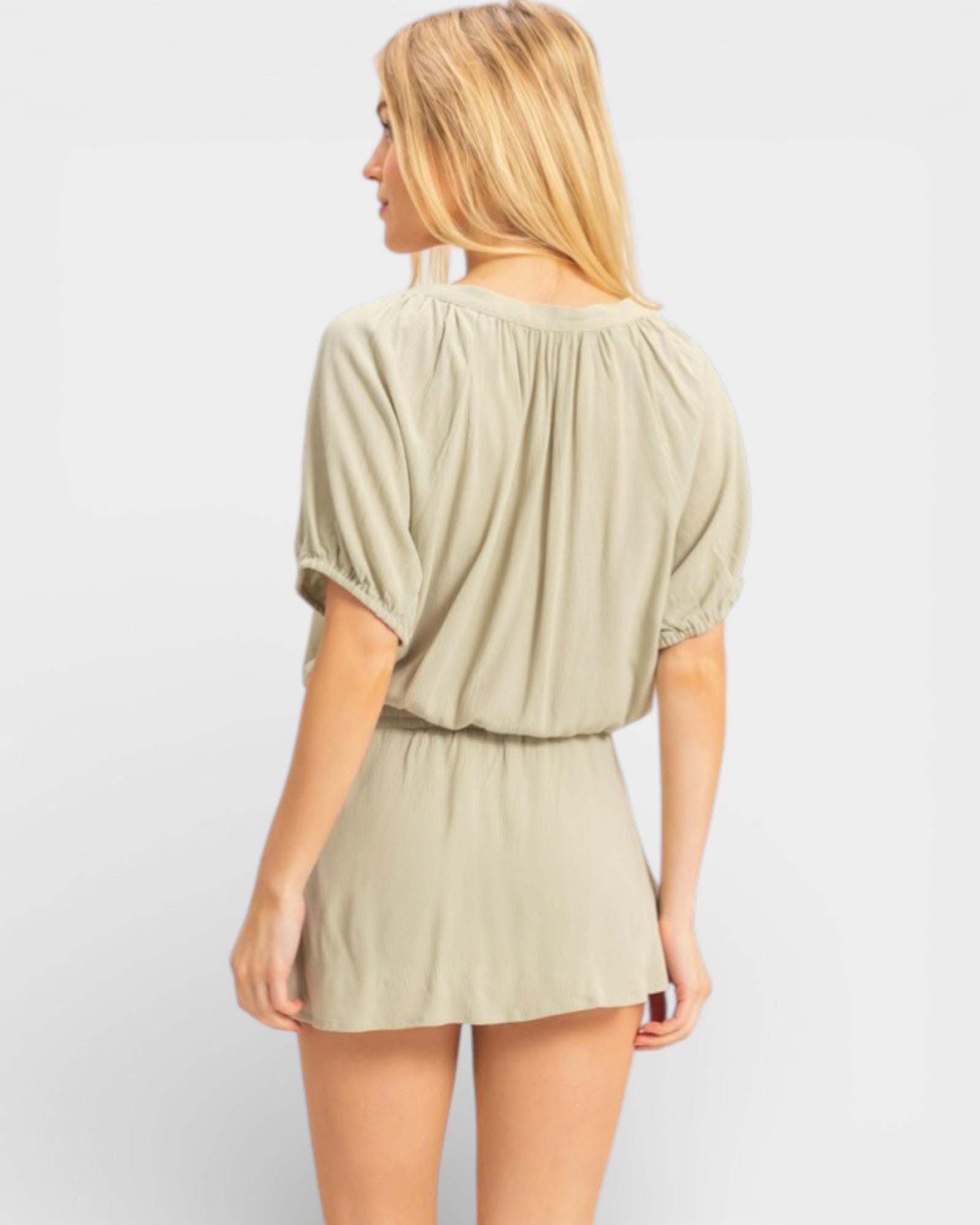 Woman wearing a beige romper on a plain background
