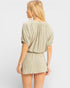 Woman wearing a beige romper on a plain background