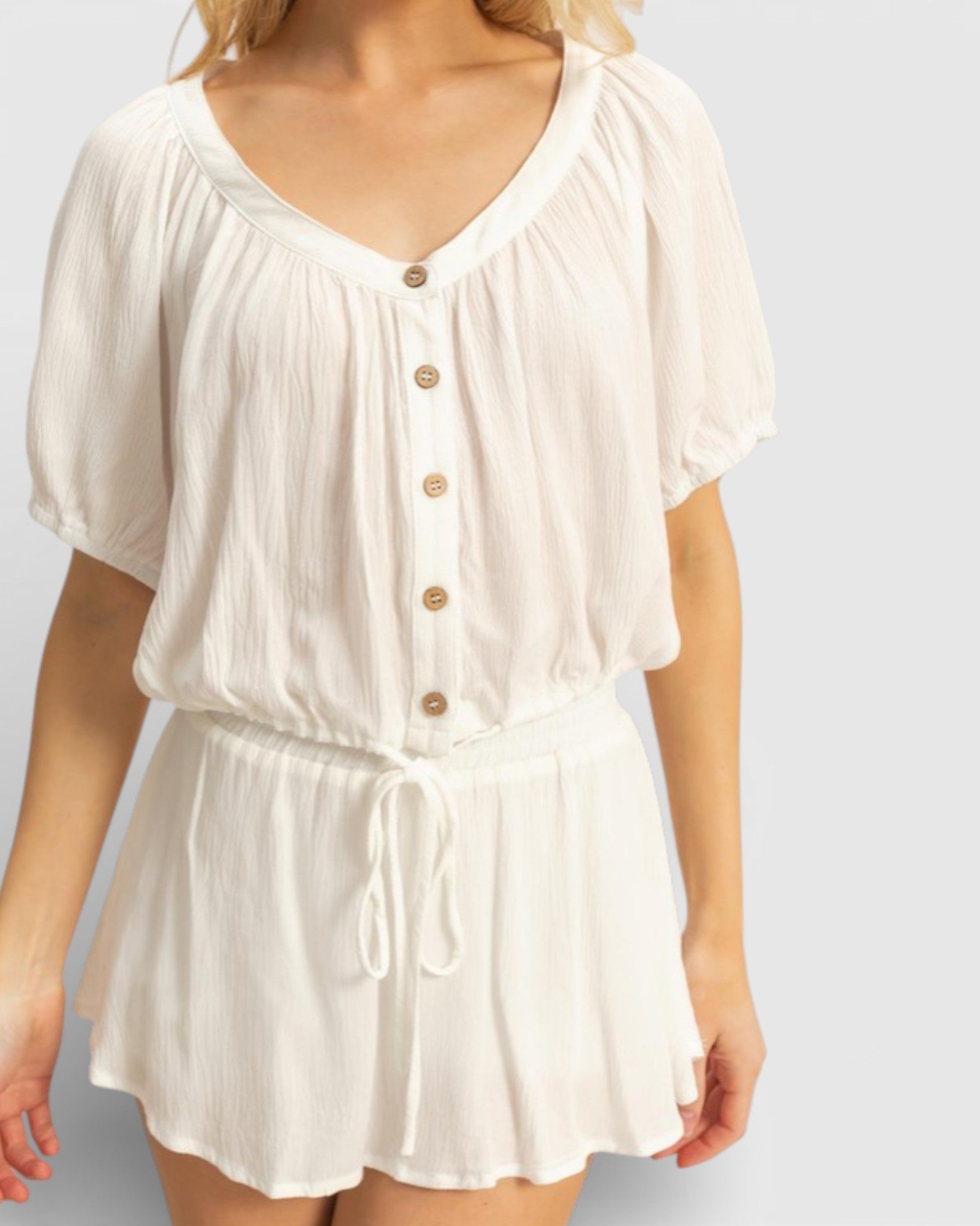 White romper with button details on a plain background