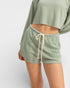 Person wearing green shorts and a matching top on a white background