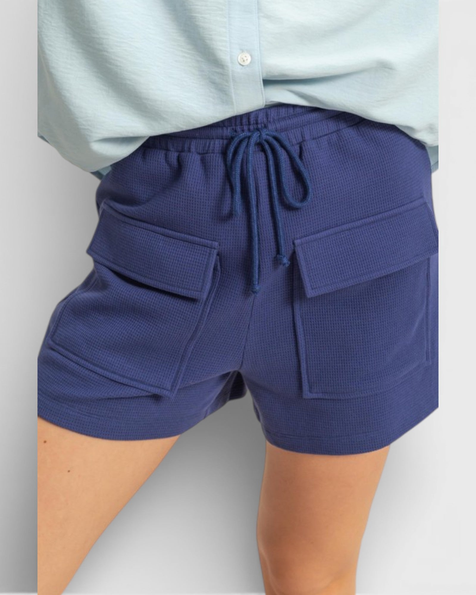 Navy blue shorts with pockets and drawstring on a light gray background
