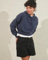 Person wearing a blue hoodie and black shorts on a neutral background