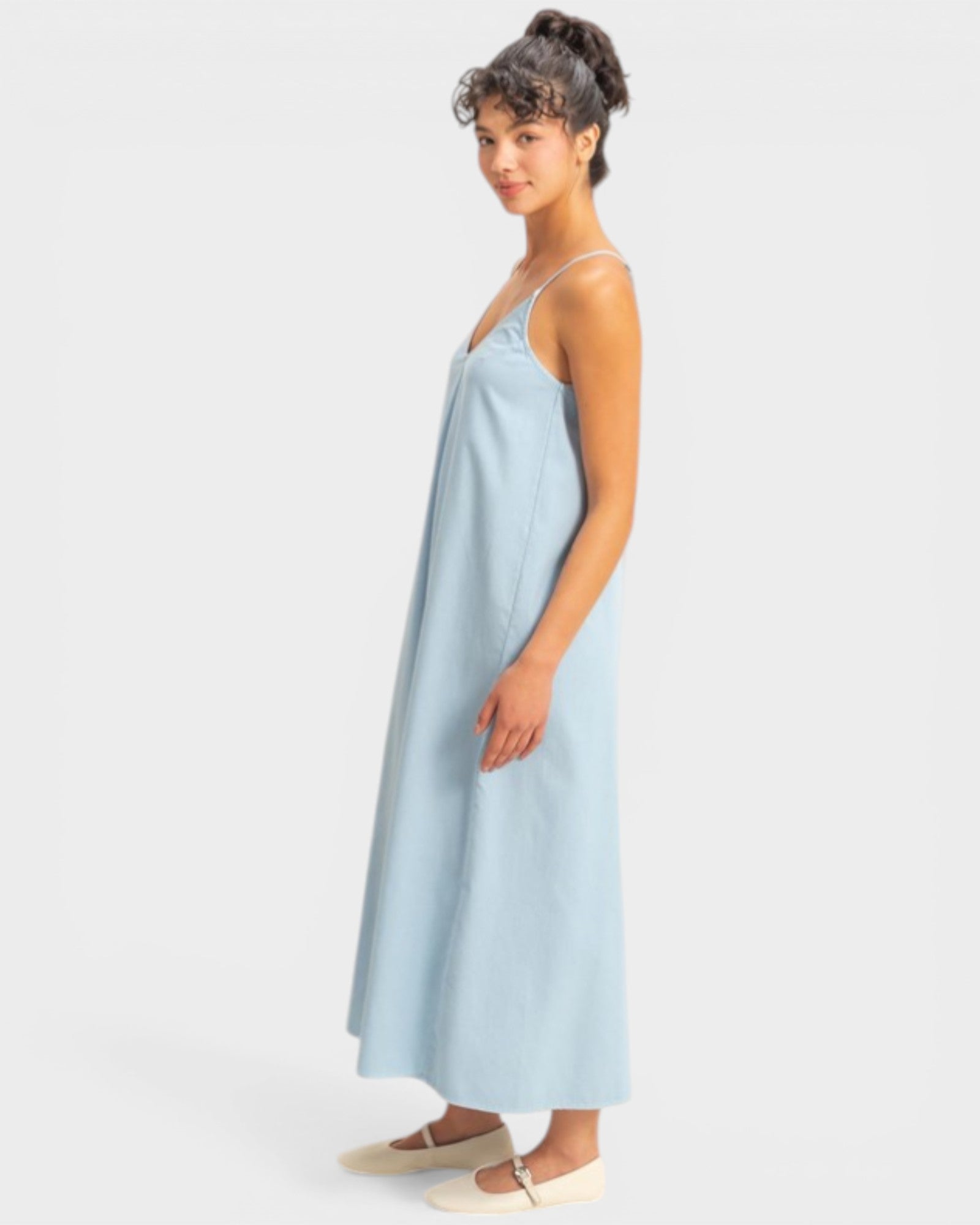 Woman wearing a light blue slip dress on a white background
