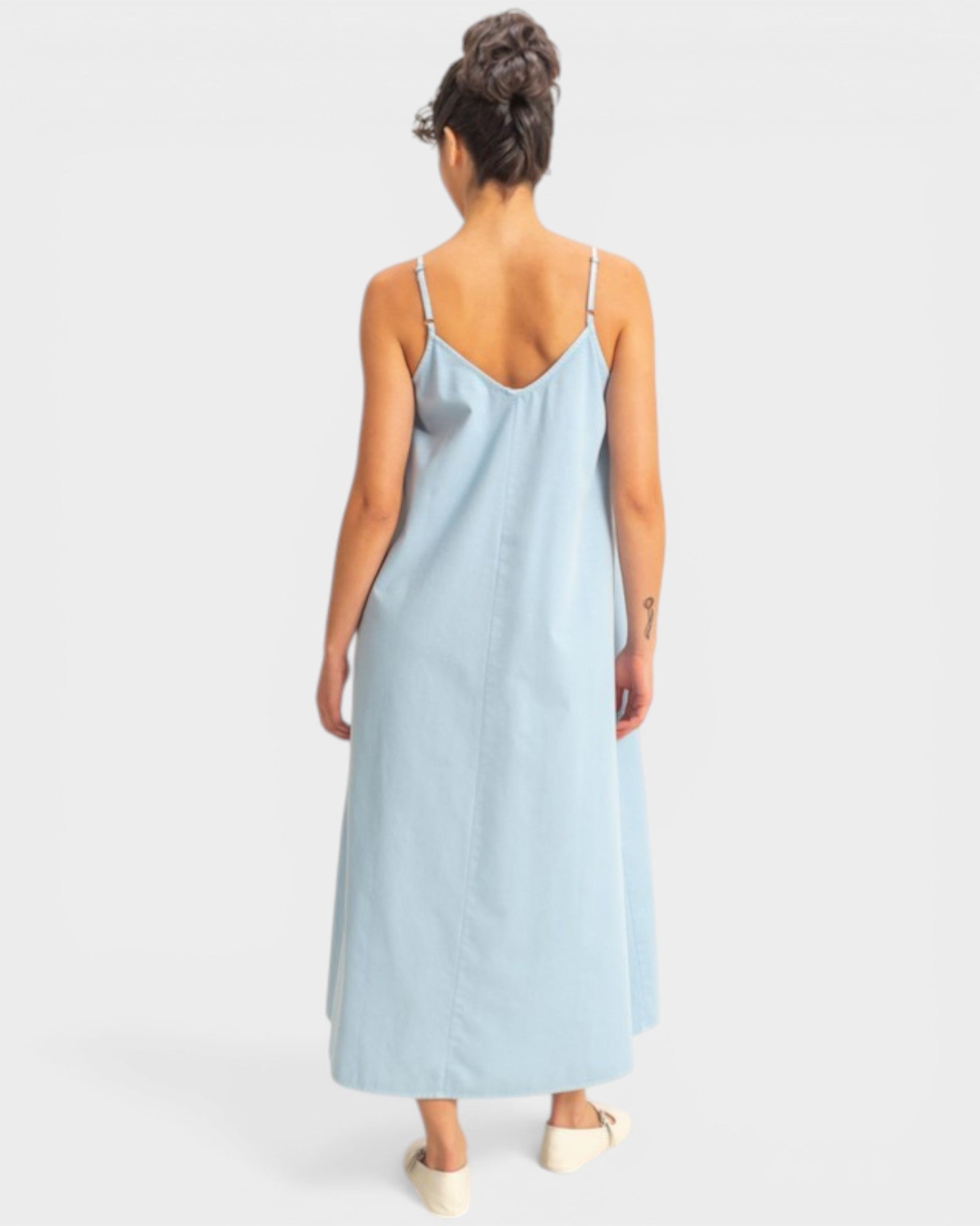 Woman wearing a light blue slip dress on a plain background