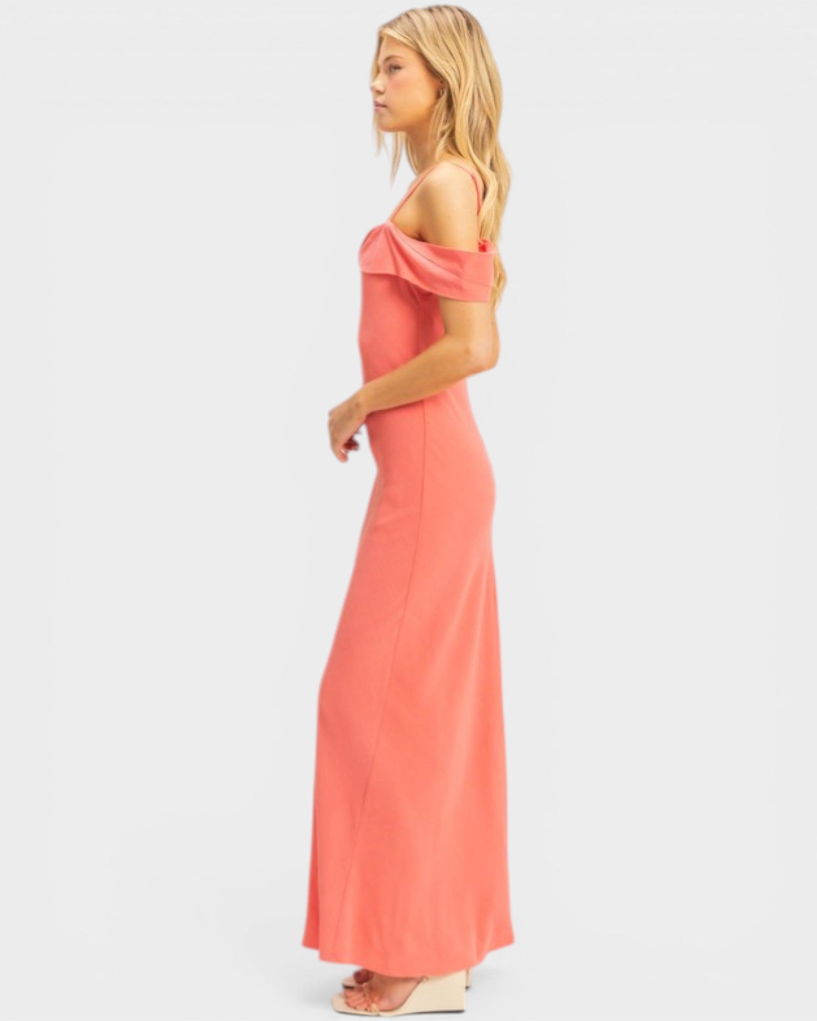 Woman wearing a coral off-shoulder dress on a white background