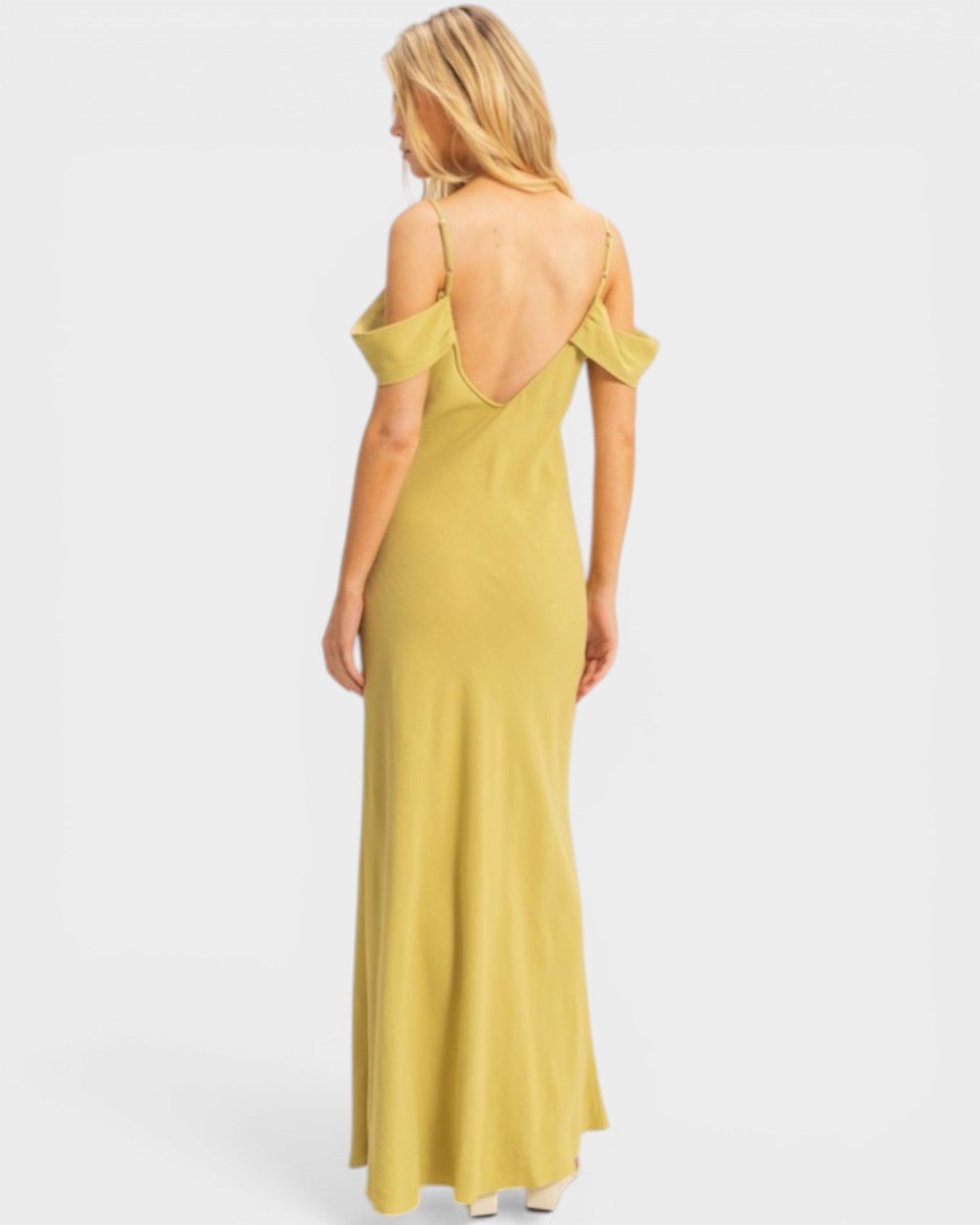 Woman wearing a yellow dress with thin straps on a white background
