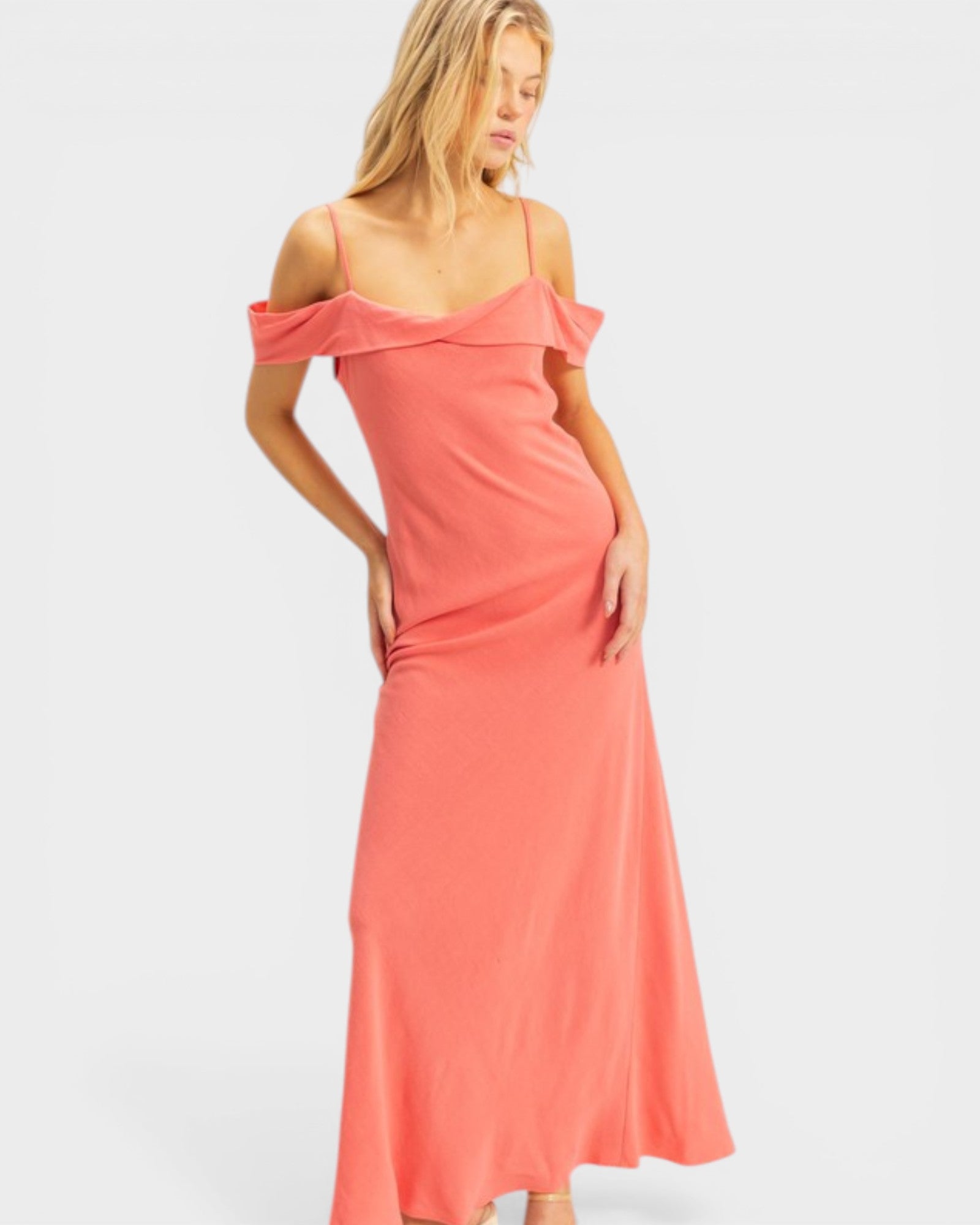 Woman wearing a coral off-shoulder dress on a white background