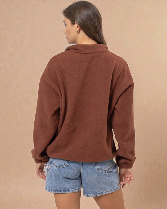 Person wearing a brown sweater and denim shorts on a beige background