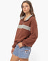 A woman modeling a brown quarter-zip sweatshirt with a light gray chest stripe and matching gray inner collar, paired with light-wash denim shorts, against a plain white studio background.