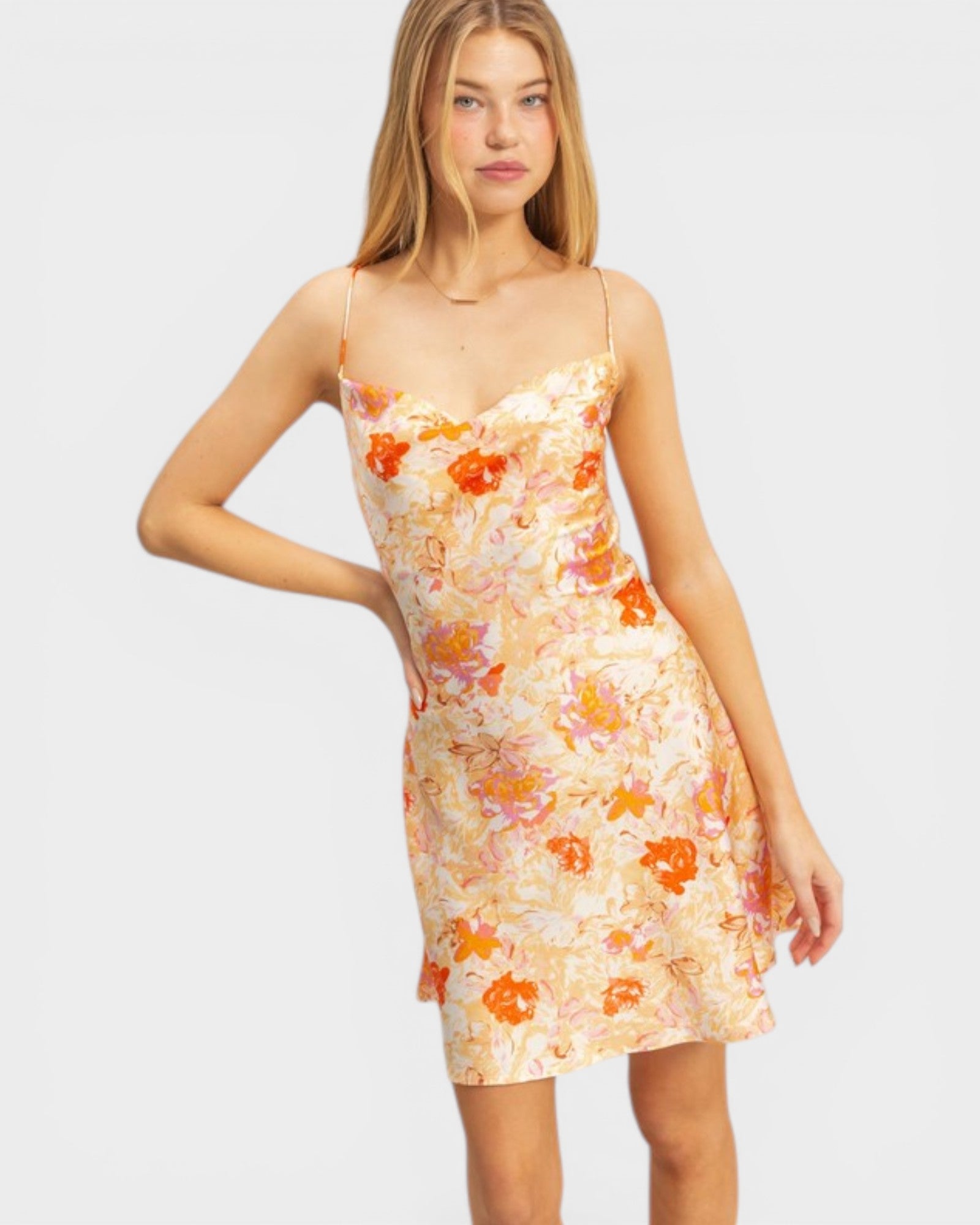 Woman wearing a floral dress with orange flowers on a plain background