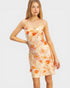 Woman wearing a floral dress with orange flowers on a plain background