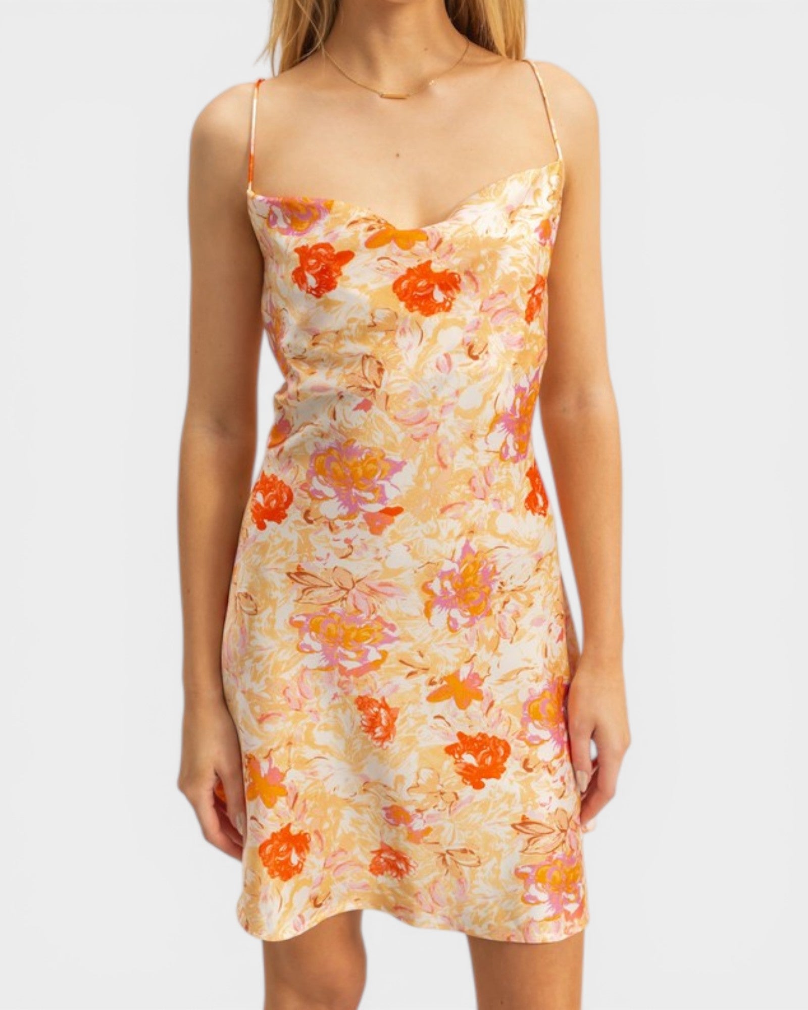 Woman wearing a floral dress with orange and pink flowers on a plain background