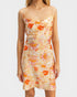 Woman wearing a floral dress with orange and pink flowers on a plain background