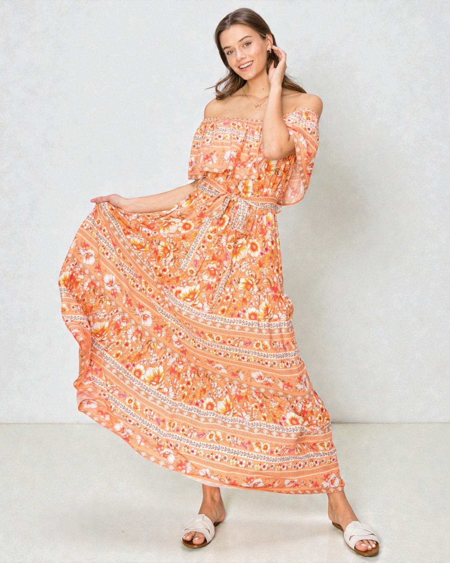 Woman wearing an orange floral off-shoulder dress on a white background