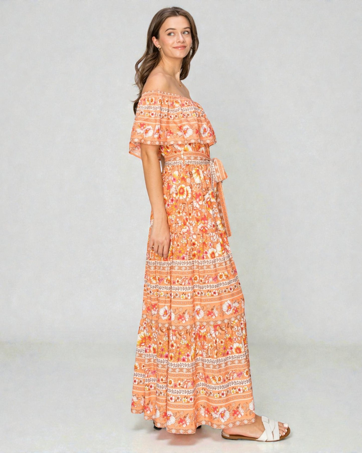 Woman wearing an orange floral off-shoulder dress on a white background
