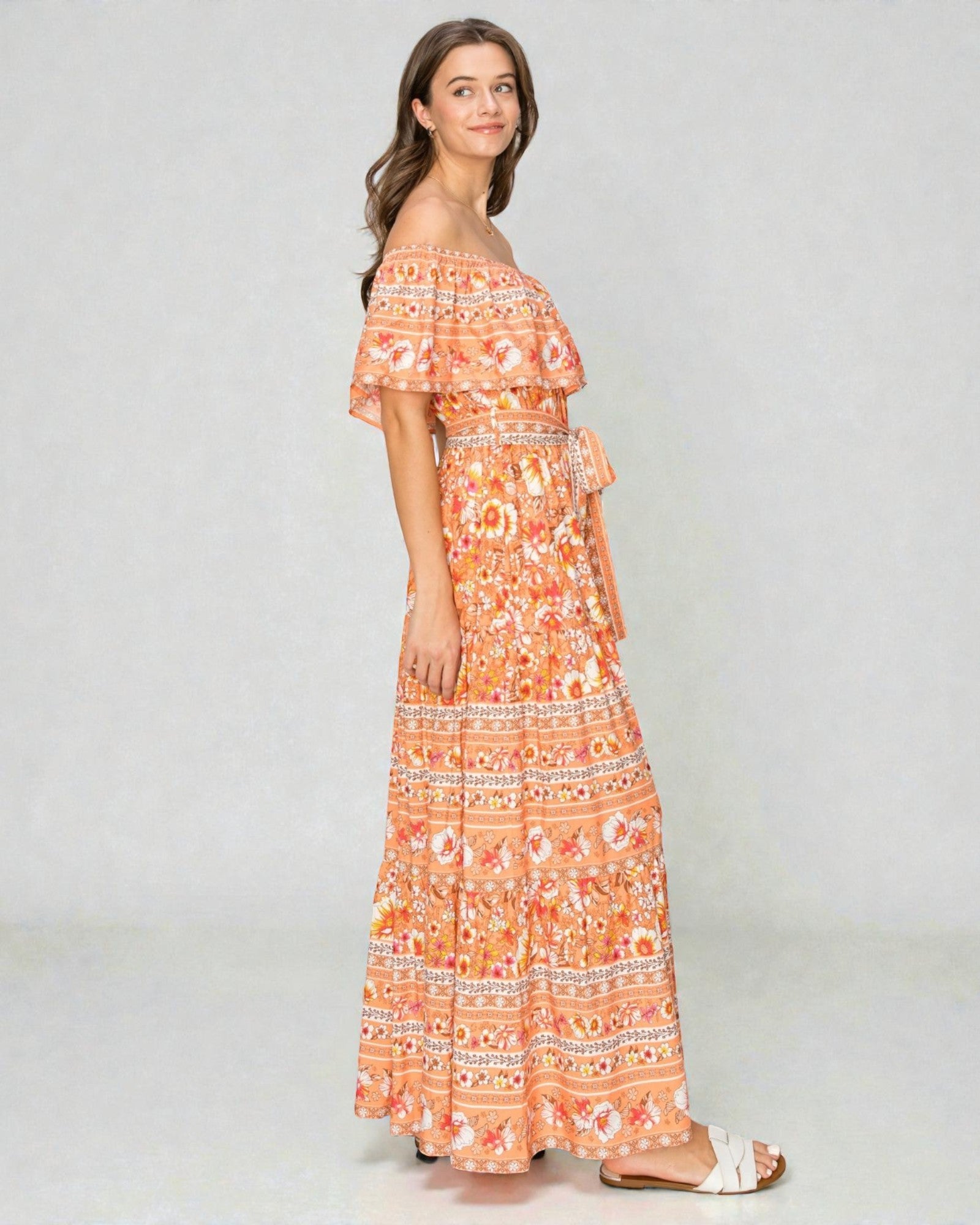 Woman wearing an orange floral off-shoulder dress on a white background