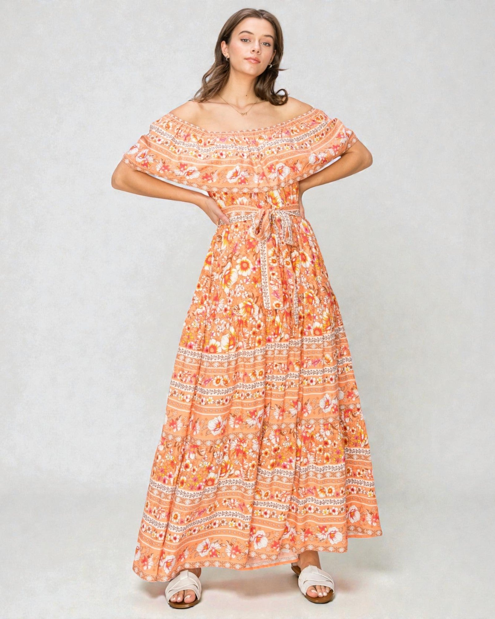 Woman wearing an orange floral dress on a white background