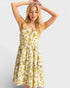 Woman wearing a yellow floral dress against a plain background