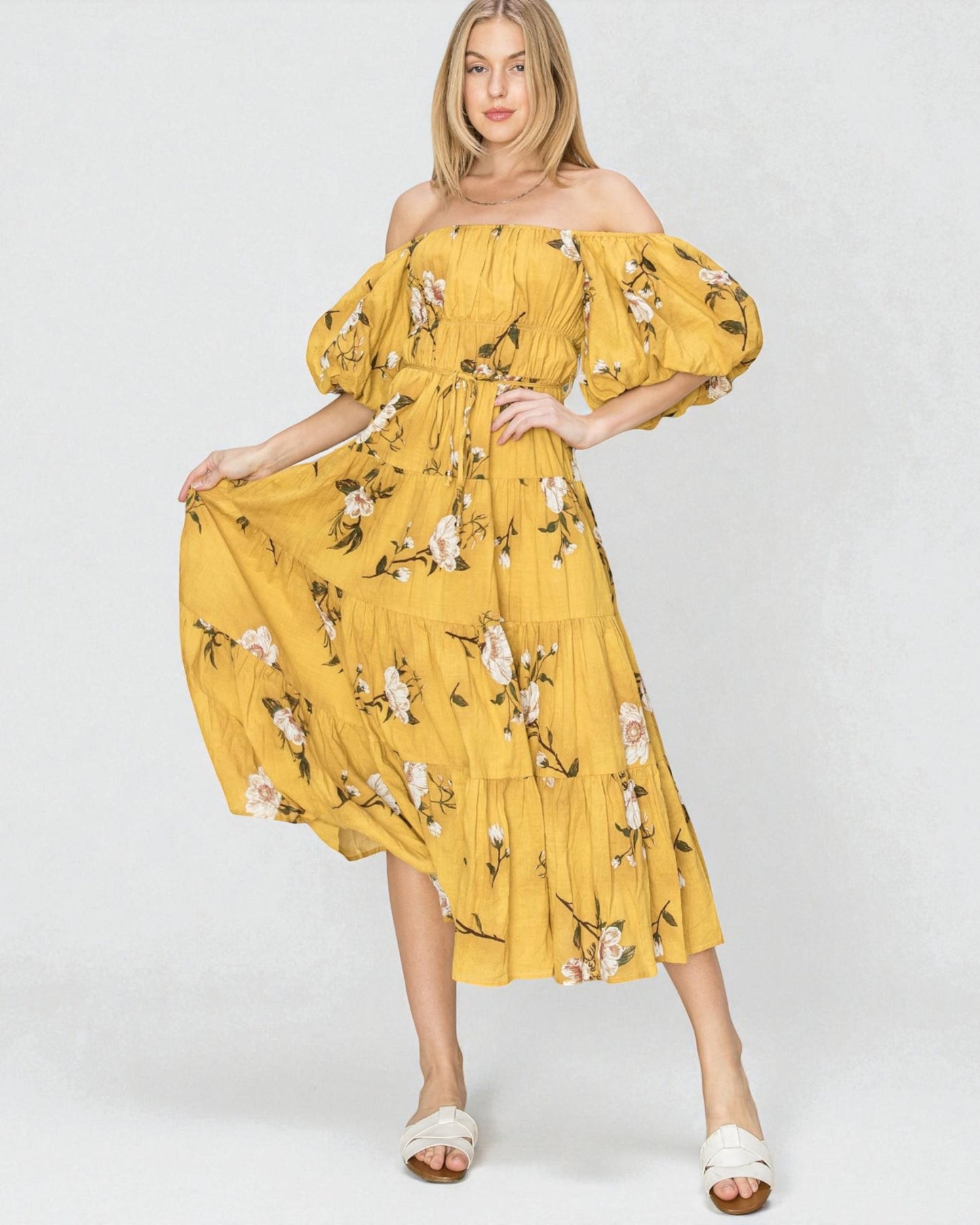 Woman wearing a yellow floral off-shoulder dress on a white background
